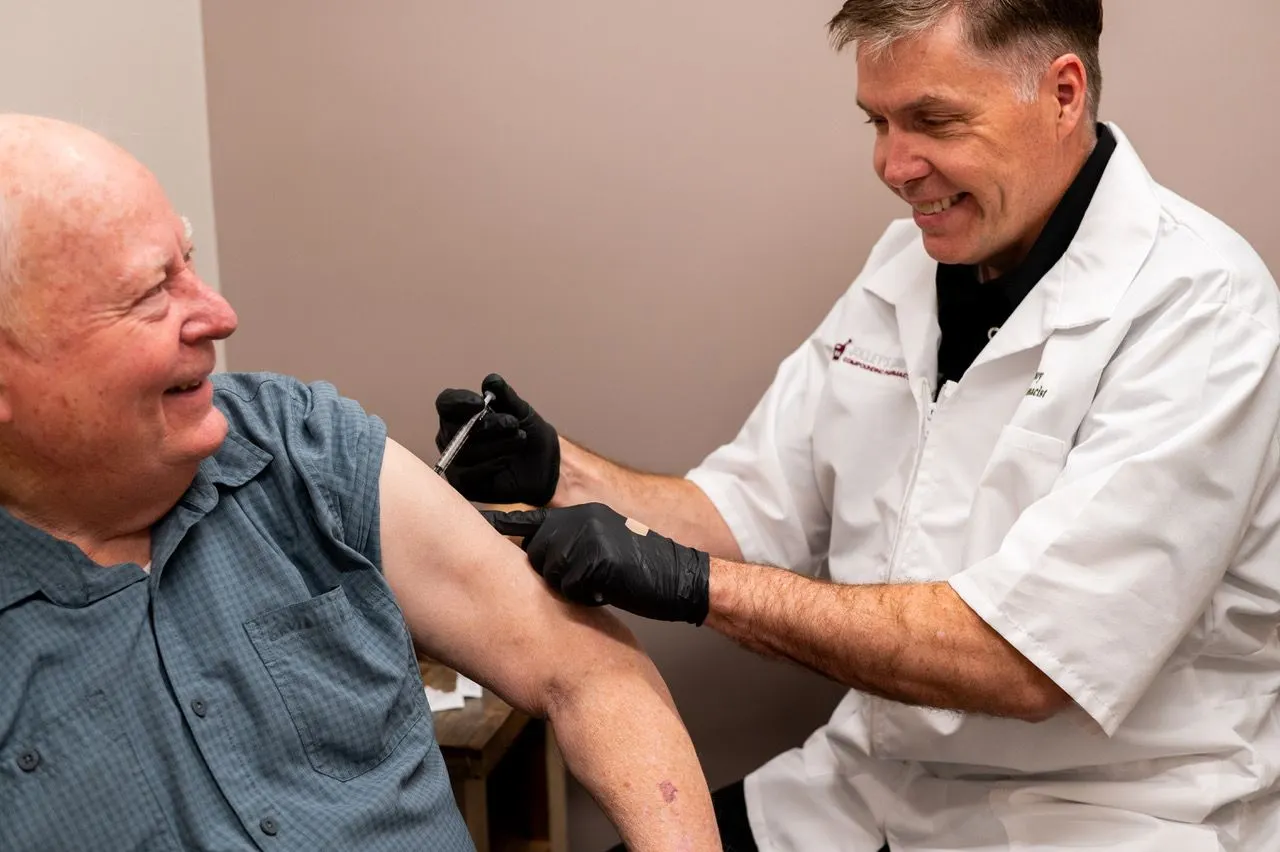 Pharmacist administering an immunization to a smiling patient
