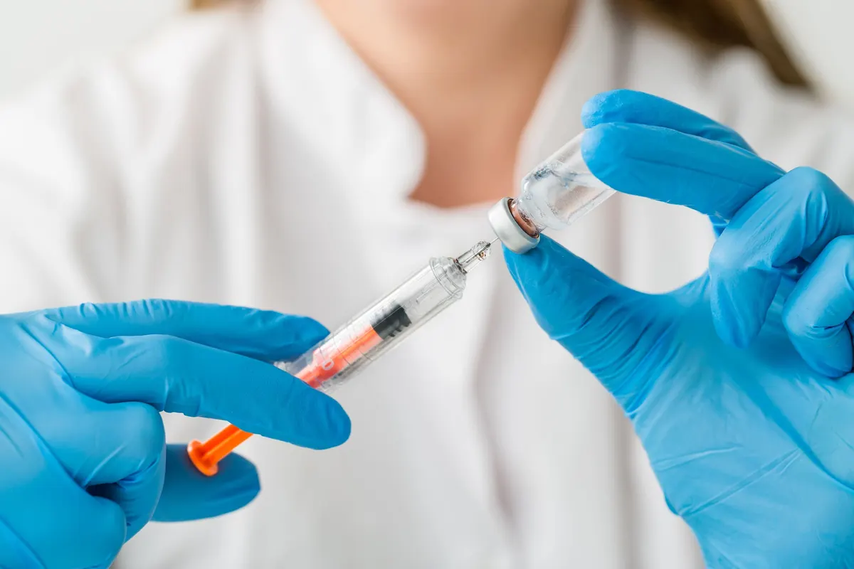 A healthcare professional preparing a vaccine dose with a syringe