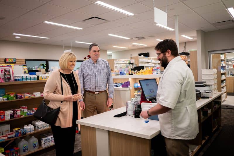 Pharmacist helping two patients at the pharmacy counter